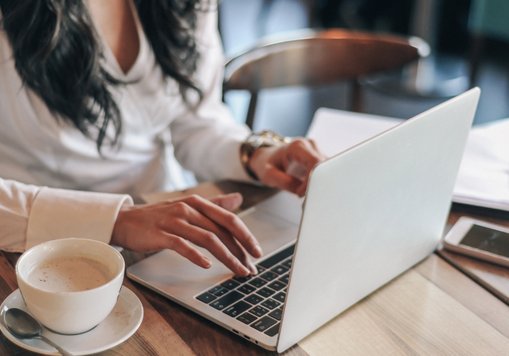 Hands working at a laptop with coffee